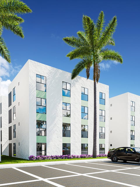 Modern white residential building with green-tinted windows, tall palm tree, purple flowers, and parking lot on clear sunny day