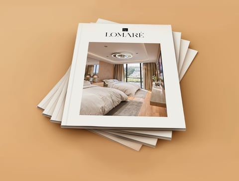 Stack of Lomare luxury interior design catalogs featuring bedroom with twin beds on tan background