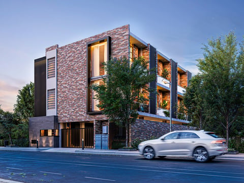 Modern brick residential building with illuminated windows, parked silver sedan, and green trees at dusk