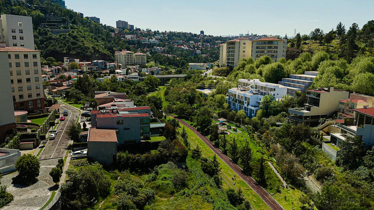 Aerial view of a residential neighborhood with multi-story apartment buildings surrounded by green trees and vegetation under a clear sky